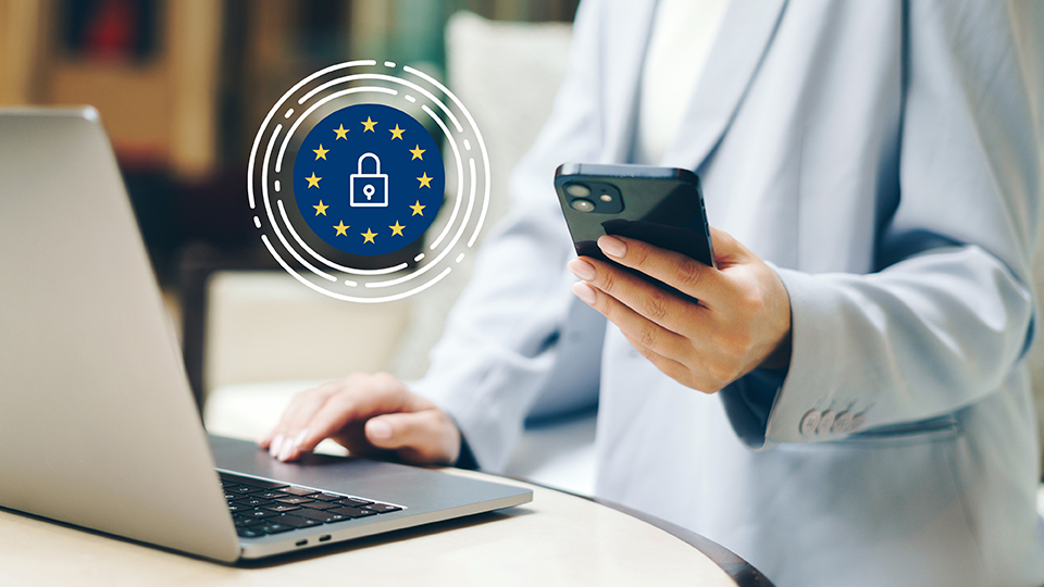 Frau mit Handy am Laptop