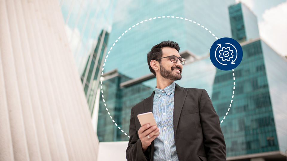 Mann steht vor einem Buerogebaeude mit Handy