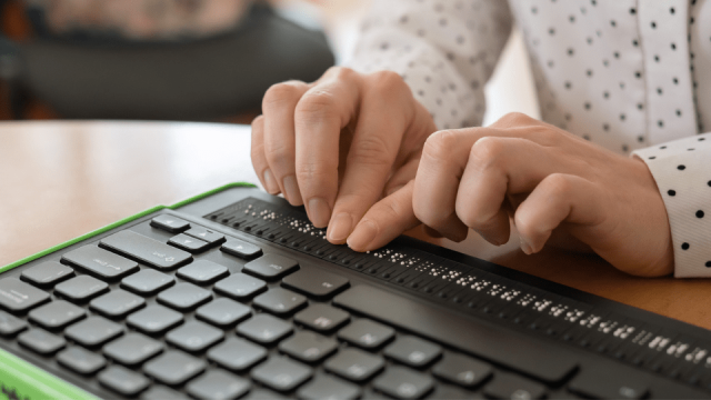 Eine Frau bedient eine Braillezeile mit ihren Händen, um ein barrierefreies PDF Dokumente zu lesen.